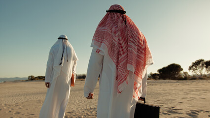 Sheiks Walking Away In The Desert With A Briefcase 
