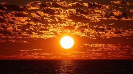 Brilliant orb illuminates dramatic sky above vast expanse of ocean water