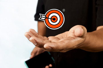 A hand presenting a target icon with an arrow, representing goal achievement, precision and strategic success.
