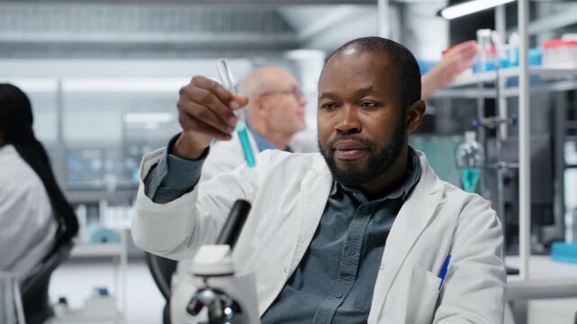 Portrait of smiling lab scientist investigating blue liquid polymer properties in test tube container. Happy man testing new synthetic material durability and viscosity in lab, camera B