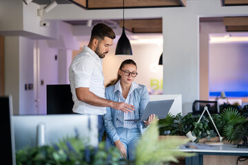Business professionals collaborating with laptop in modern creative office
