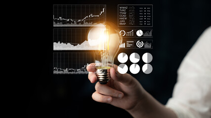 A person holds a glowing light bulb as business analytics and graphs appear on a dark background, symbolizing innovation and creative ideas in the finance industry. Impute