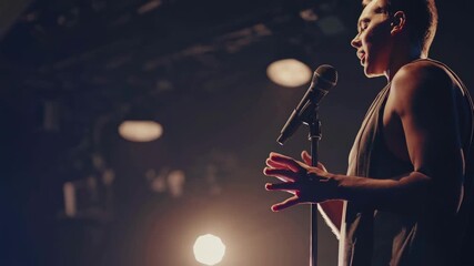 A performer sings passionately on stage, captured from a side angle. Warm lighting creates a dramatic atmosphere, ideal for a music video concept.