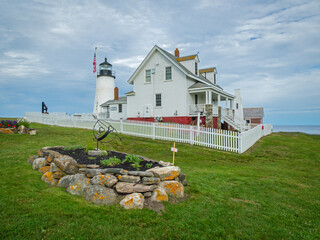 Pemaquid Point Lighthouse in Bristol ME on an early summer day in June with fresh flowers and lush foliage