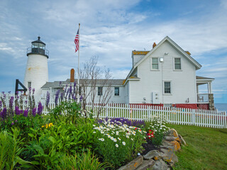 Pemaquid Point Lighthouse in Bristol ME on an early summer day in June with fresh flowers and lush foliage