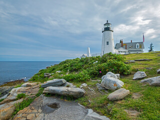 Pemaquid Point Lighthouse in Bristol ME on an early summer day in June with fresh flowers and lush foliage