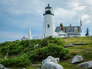 Pemaquid Point Lighthouse in Bristol ME on an early summer day in June with fresh flowers and lush foliage