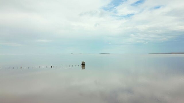 Abandoned wooden structure standing isolated in the pink waters of Tuz salt lake in Turkey