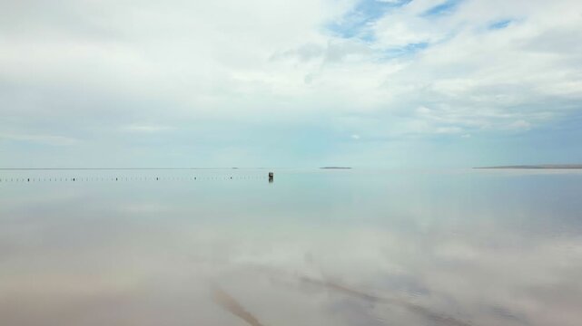 Abandoned wooden structure standing isolated in the pink waters of Tuz salt lake in Turkey