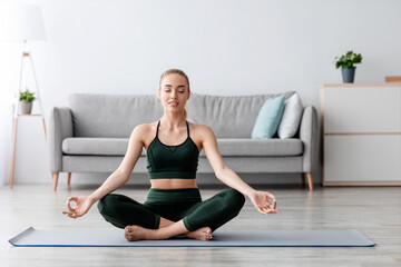 Calm caucasian pretty young blonde lady with closed eyes practicing yoga, breath, exercising at...