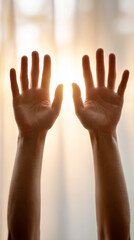 Silhouetted arms raised against sunlit curtain for inspirational concepts