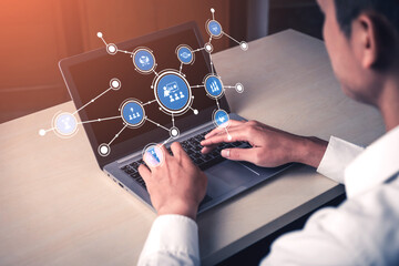 A focused individual works on a laptop, engaging with digital graphics that illustrate business analytics and social media connections in a modern workspace. Tessel