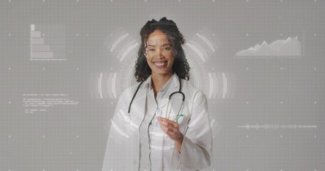 Smiling woman doctor posing in studio with HUD, holding pen, wearing lab coat and stethoscope