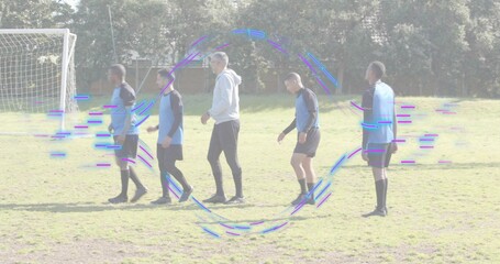 Walking six players in blue bibs and coach in grey hoodie across soccer pitch, purple-blue glitch