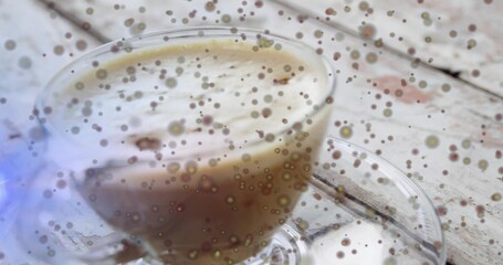 Showing glass coffee cup resting on clear glass saucer on whitewashed tabletop, frothy swirl