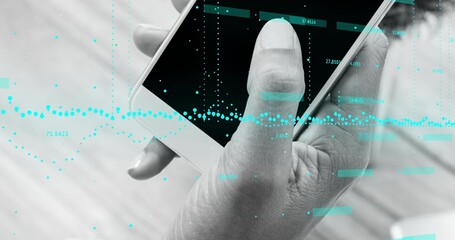 Holding right hand gripping white smartphone over light wood table, showing cyan data overlay