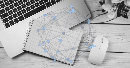 Showing notebook lying on wood desk with silver laptop white mouse, potted flowers, network overlay