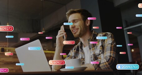 Talking man typing on laptop holding phone at cafe, wearing plaid shirt, coffee cup, AR bubbles