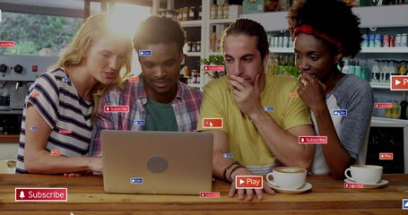 Leaning group of four people gathering around silver laptop at cafe counter with social stickers