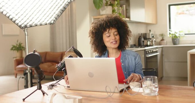 Live stream starting, woman adjusting mic by softbox light at home, sipping water before speaking