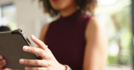 African American woman adjusting grip on gray tablet case, tapping and browsing content at home
