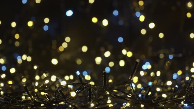 A selective focus shot of tangled string of Christmas led lights in the darkness. Christmas and New Year lighting. Festive atmospheric background