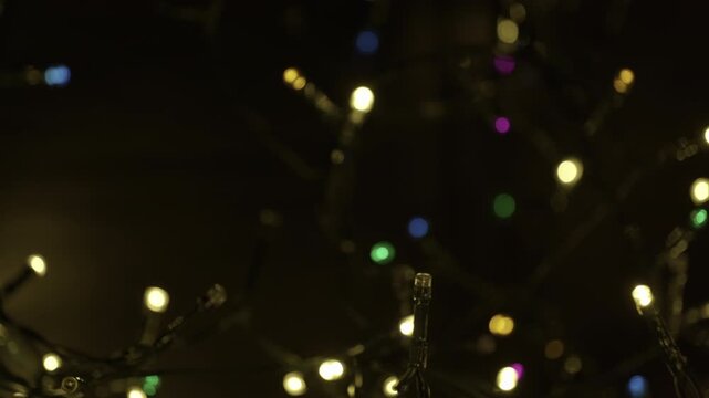 A selective focus shot of tangled string of Christmas led lights in the darkness. Christmas and New Year lighting. Festive atmospheric background