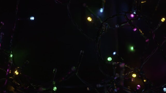 A selective focus shot of tangled string of Christmas led lights in the darkness. Christmas and New Year lighting. Festive atmospheric background