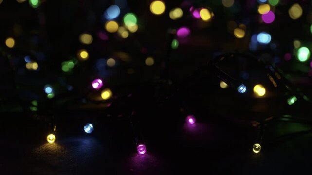 A selective focus shot of tangled string of Christmas led lights in the darkness. Christmas and New Year lighting. Festive atmospheric background