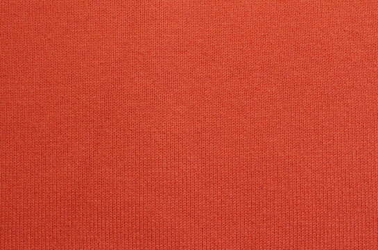Close-up orange knitted texture background. Orange knitted sweater made of cotton, acryl, and nylon blended yarn.