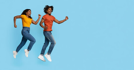 Emotional stylish milennial black couple running together towards copy space for advertisment on...
