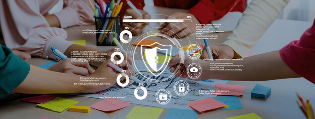 A diverse group of individuals collaborates on a project at a table filled with colorful sticky notes while examining a digital graphic focused on security and data protection. Trope
