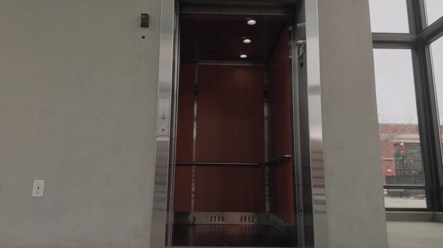Static slow motion shot of elevator doors opening, pausing, and closing inside a modern building