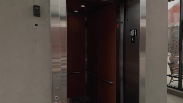 Gentle slow motion pan as elevator doors open and close inside a quiet modern building