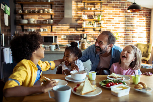 Father and children laughing at breakfast in home kitchen