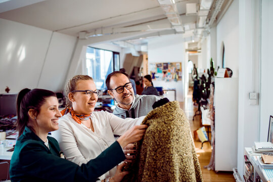 Team of fashion designers reviewing fabric in creative studio