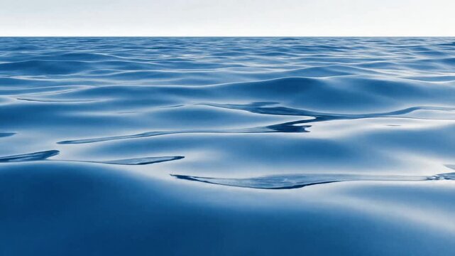 Close-up view of tranquil blue ocean water with subtle ripples reflecting light under a clear sky, creating a serene and calming natural scene.
