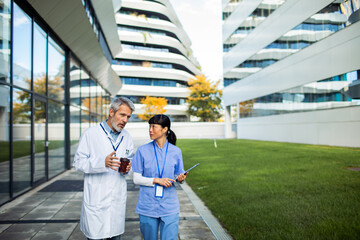 Doctor and nurse discussing work on hospital campus