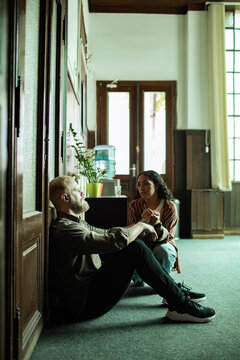 Two coworkers talk while sitting on an office hallway floor