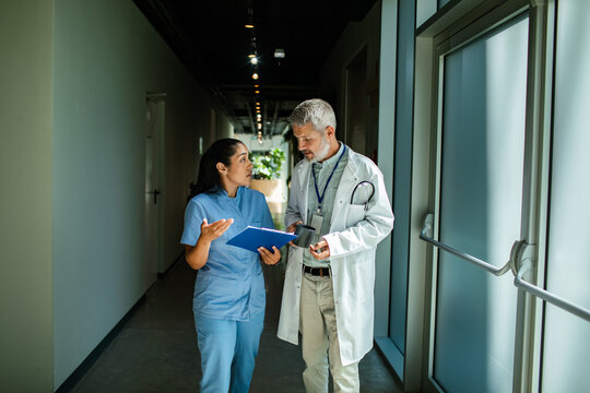 Doctor and nurse discussing patient chart in hospital hallway