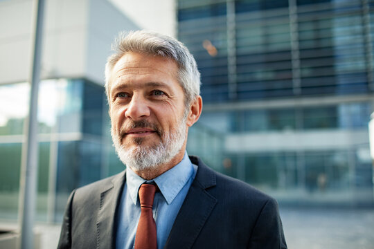 Confident senior businessman smiling outside office