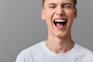 Laughing man with wide smile wearing a white tee, conveying joyful energy and carefree mood in a simple studio setting