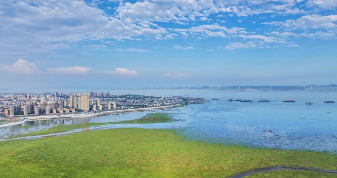 Aerial time-lapse of Lushan City beside Poyang Lake, summer wetlands, blue sky, and serene lakeside urban scenery in Jiangxi Province, China