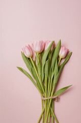 パステルピンクの背景に花束を置いた縦型トップビュー チューリップの上品な春ビジュアル. 生成AI