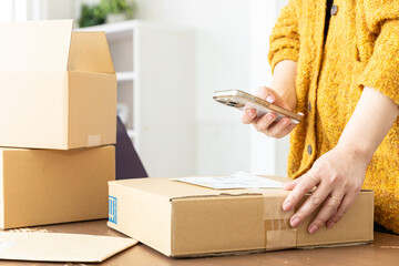 スマホで発送準備する女性