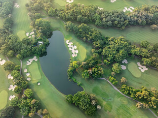 Aerial view of golf course fairway and green with sand traps pond and trees