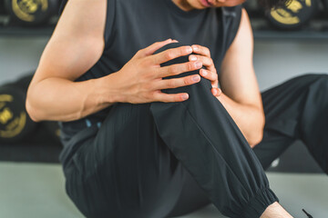 Young Asian man suffering from knee pain while training at the gym