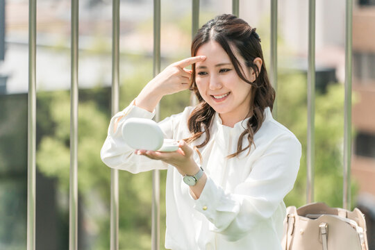 A woman touching up her makeup (forehead, wrinkles, hyaluronic acid)