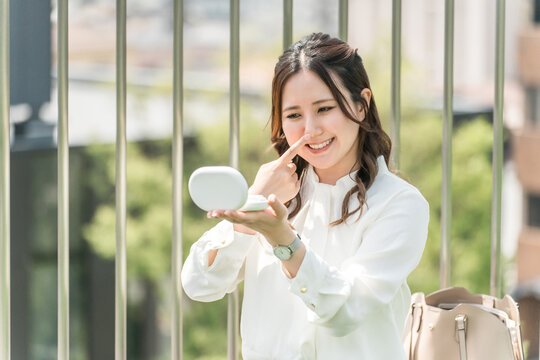 A woman touching up her makeup during a break (nose surgery, plastic surgery, nose tip)