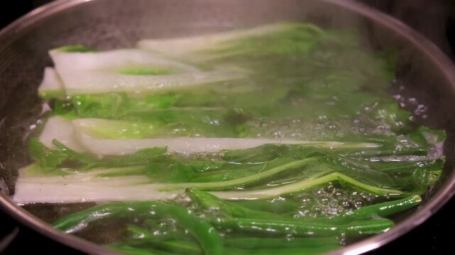 Cooking vegetables in boiling water at home for simple meal preparation in kitchen. Fresh vegetables are placed in boiling water to cook. Steam rises as they soften for a quick and healthy meal in the
